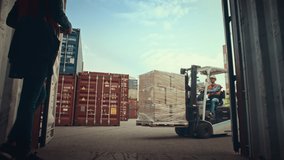 Forklift Driver Loading a Shipping Container with a Pallet with Boxes in Logistics Terminal. Female Industrial Supervisor Helping the Process. VFX Double Girder Gantry Cranes Work in the Background. - Powered by Shutterstock - Get 15% off with code: PIKWIZARD15