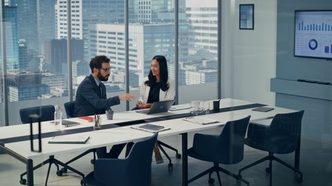 Businesspeople in Modern Office: Businesswoman and Businessman Use Laptop Computer, Talk. Top Manager and Partner Investor Discuss e-Commerce Software Global Investment Strategy. Elevating Wide Shot