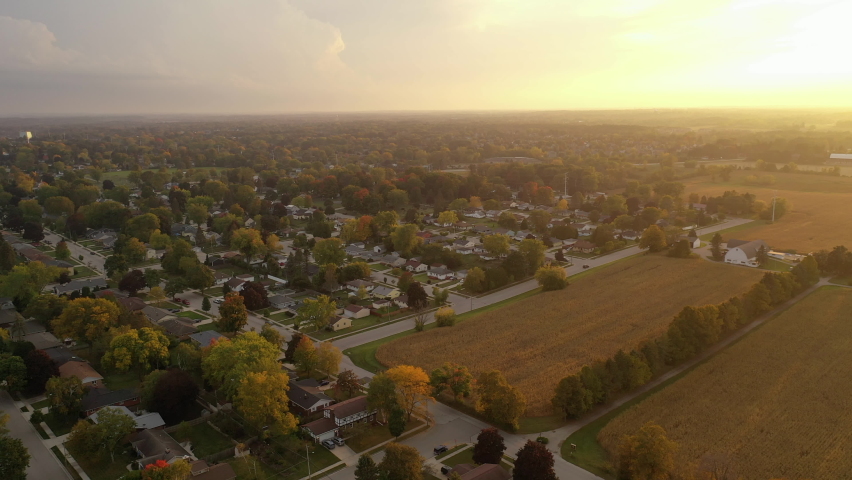 Aerial Midwest countryside in fall season. Typical midwestern autumn landscape. Agricultural fields, farm, suburban neighborhood at sunset.