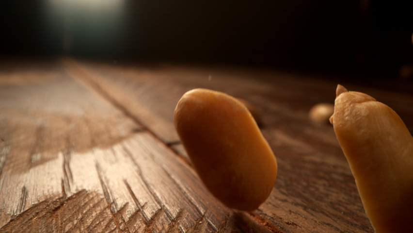 Peanuts falling onto wooden surface in slow motion. Shot with Phantom Flex 4K camera. Royalty-Free Stock Footage #1080336959