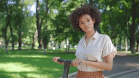 Portrait of young black woman smiling, standing with electric scooter in park - Powered by Shutterstock - Get 15% off with code: PIKWIZARD15