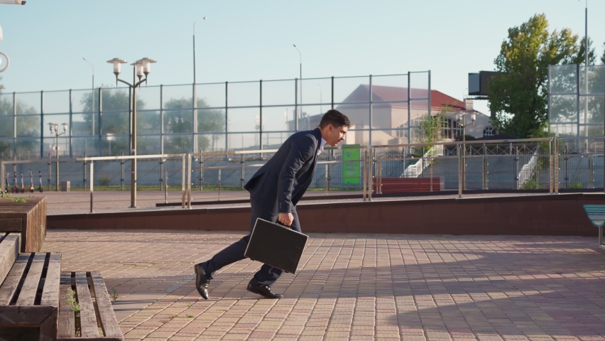 Successful young businessman is running fast with a business briefcase in his hands, being late for an important meeting. Entrepreneur or office worker rushing to work jumping over an obstacle. Royalty-Free Stock Footage #1080343691