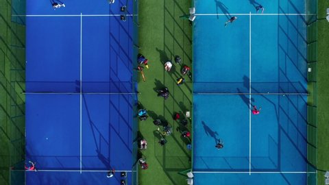 Aerial view of unrecognizable tennis athletes seen from above playing a game of paddle tennis at an outdoor paddle tennis court 