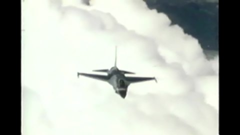 CIRCA 1997 - A USAF F-16 Fighting Falcon flies through the clouds and conducts an air strike.