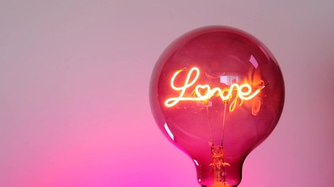 Valentine's Day.romantic background in pink colors. Light bulb with the inscription love on a pink background.Love symbol. Love and relationship symbol. High quality 4k footage
