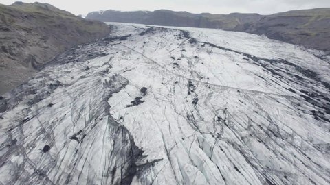 Aerial view over darkened, sooty glacier surface, in Iceland - reverse, drone shot