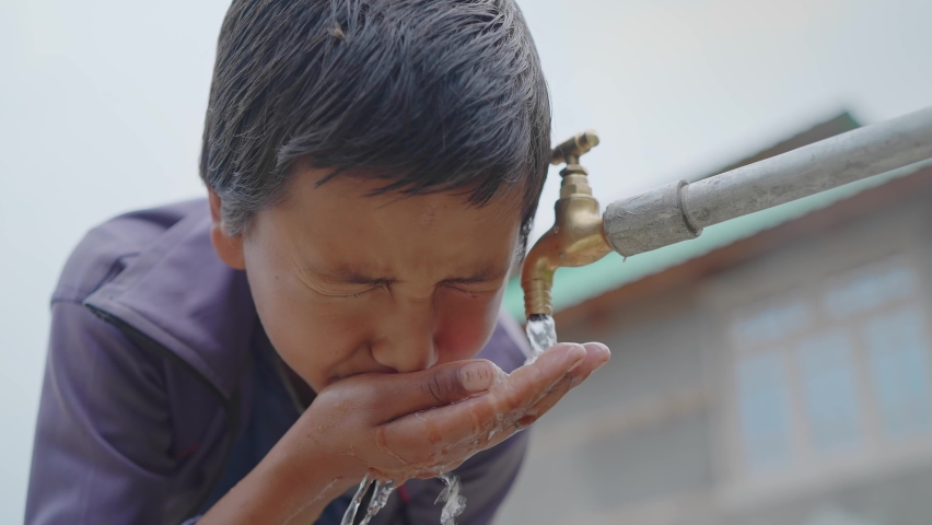 close up shot of a young little boy drinking clean fresh water from a running tap in a rural village. Concept of a natural resources conservation Royalty-Free Stock Footage #1080363524