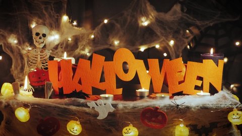 Happy halloween. Celebrating halloween night. Halloween party decorations with pumpkins, cobwebs, spiders and skeleton. Bright orange word Halloween against black scary horror background