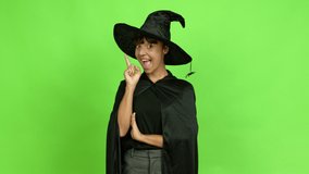 Young woman wearing witch hat intending to realizes the solution while lifting a finger up over isolated background. Green screen chroma key