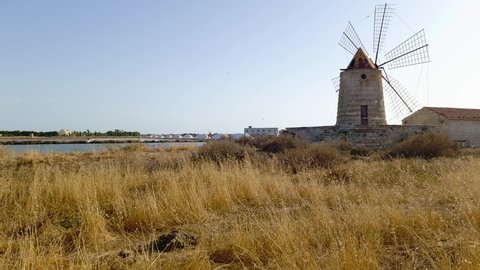 Bird flying over Mulino Maria Stella windmill in front of saline in province of Trapani, Sicily. Italy