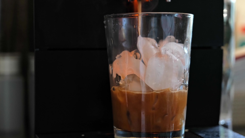 Ice Coffee preparation, pouring coffee in ice cubes from coffee machine, make cold brew coffee, in transparent glass | Shutterstock HD Video #1080372296