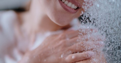 slow motion of a woman taking a shower, beautiful girl washing and enjoy herself under a shower, close up of hands, shoulder and body details