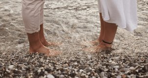 Caucasian couple happily standing on beach soaking feet in the ocean 