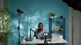 Black influencer talking about studio light for vlog review on camera. African american vlogger reviewing professional tool for videography equipment, holding gear for recommendation