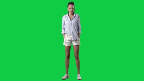 Happy confident stylish woman in blue shirt and shorts posing and modelling at camera. Full body on green screen chroma key background