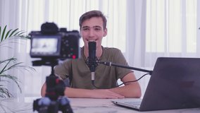 Man blogger videotapes his vlog at home. Teenage boy recording his video blog. Young man speaks in front of a video camera for his blog channel. Vlogger makes online streaming using smartphone 