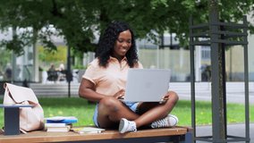technology, education and people concept - happy smiling african american student girl with laptop computer having video call in city
