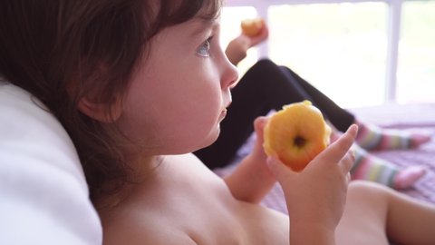 The child wipes his nose and coughs. The child eats fruit during a cold. Close-up of the face of the child who eats