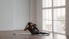 Sporty Young Black Woman Doing Elbow-To Knee Abs Crunches Exercise While Training At Home, Motivated African American Female Making Abdominal Muscles Workout, Exercising On Fitness Mat, Slow Motion