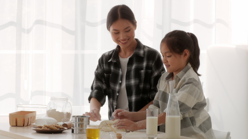 Chinese Mom And Daughter Baking Cake And Having Fun With Flour Touching Each Other's Noses Standing In Modern Kitchen At Home. Asian Family Of Two Bonding Cooking Together On Weekend Royalty-Free Stock Footage #1080382307