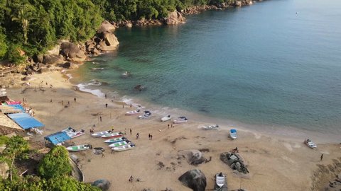 Time lapse aerial view of a beautiful Brazilian beach. Clear ocean water. Boats on sand. Rocks and vegetation on background. Landscape.