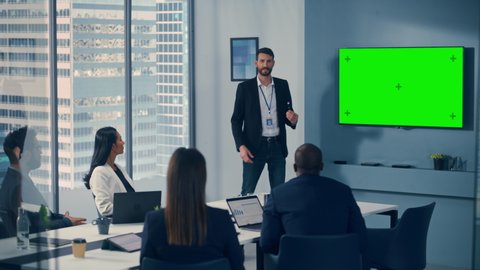 Office Conference Room Meeting Presentation: Handsome Businessman Talks, Uses Green Screen Chroma Key Wall TV. Successfully Presenting e-Commerce Product to Group of Multi-Ethnic Investors