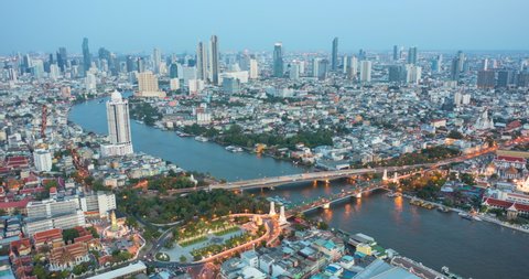 Hyperlapse aerial view day to night time lapse landmark financial business district with skyscraper over Chao Phraya River at Bangkok, Thailand at sunset. Amazing Drone Footage over the City skyline.