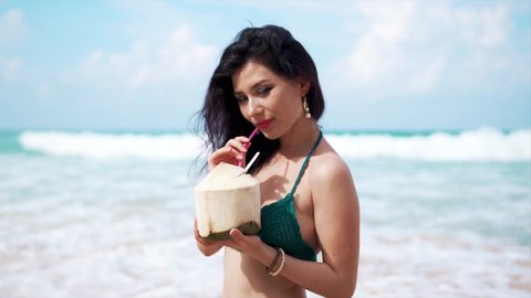Beautiful woman with coconut on a beach. Tourism and recreation in Thailand. Charming cute Asian woman travel around the islands. The girl enjoy life and has fun. Paradise beaches and white sand