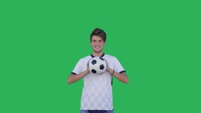Close-up of Soccer player performs tricks with the ball on a green screen background, Chroma Key. Young caucasian man practicing football skills. 4K UHD slow motion RAW graded footage