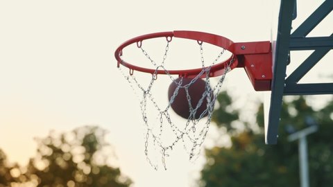 Basketball ball hits into hoop outdoors. Successful throw. Making a goal. Basketball Court. The decisive moment of the game. Street basketball. Basketball player scores a goal on the arena.
