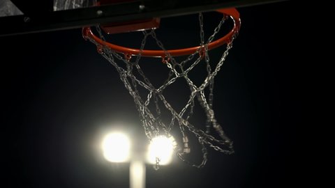 Throw the ball into a basketball hoop on the spotlights background. Basketball player scores a goal on the arena. The decisive moment of the game. Basketball Court.