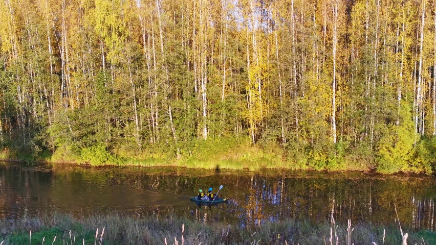 a boat is sailing on a calm river in an autumn forest and two people are rowing with oars