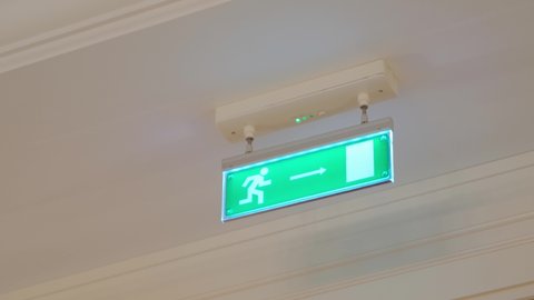 emergency exit, fire escape direction green lighting sign indicating close up. person pointer icon with an arrow towards the fire evacuation. 4k dolly shot