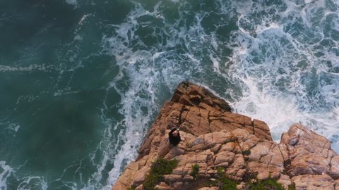 Unusual natural beauty with the Atlantic Ocean and rocky surroundings. Aerial of a man standing at the edge of rocky formation. Europe, Portugal, Sintra, Ursa Beach. High quality 4k footage