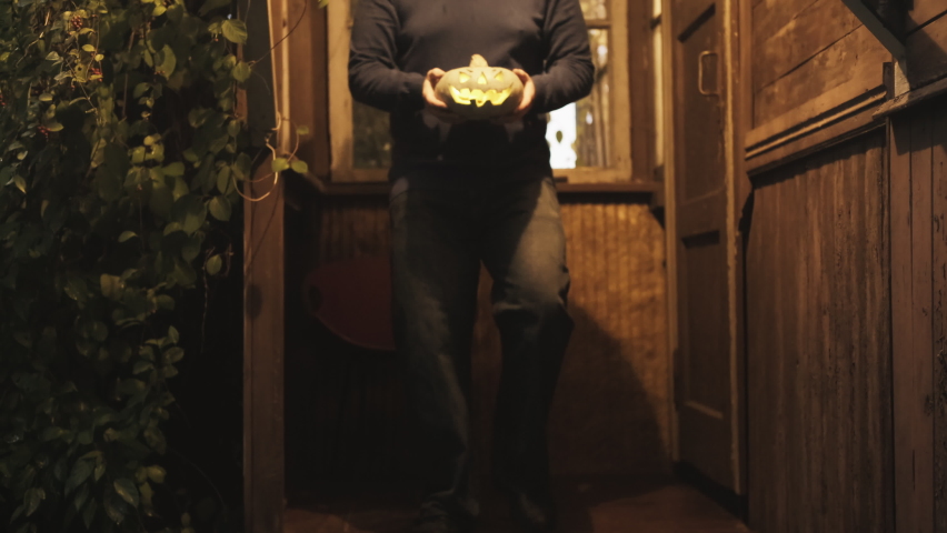Man In a cowboy hat with a pumpkin for halloween on the porch of an old house. The concept of the feast of the night of all Saints. Sweet or nasty