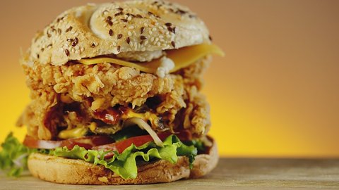Fried crispy chicken burger with cheddar cheese, lettuce, tomato and onion
