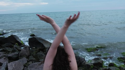Sea inspiration. Harmony freedom. Nature balance. Back view of dancing woman hand movements at ocean beach enjoying waves breeze rocky shore.