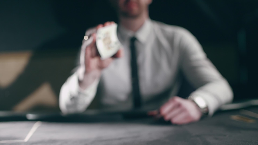 A professional croupier is working with cards. Close up of holdem dealer with playing cards on black table. Concept of casino gambling or poker and entertainment. Slow motion Royalty-Free Stock Footage #1080440444