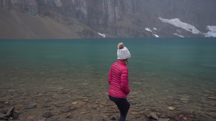 Woman on Iceberg Lake Coast, Glacier National Park, Montana ,USA on Cold Autumn Day, Slow Motion