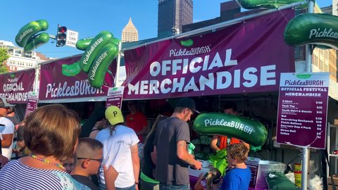 Pittsburgh , Pennsylvania , United States - 08 21 2021: Men buying a Picklesburgh ballon, official merchandise of the Picklesburgh food festival for his son from the vendor