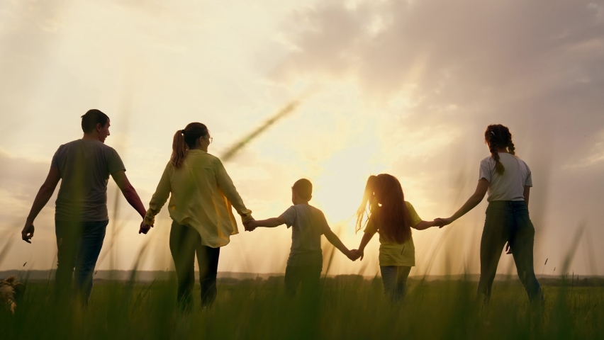 Big happy family. Summer people in park at sunset. Family is walk on green grass in natural park. Family fun, joy in nature. Healthy young family at sunset. Concept of happy people in nature in grass