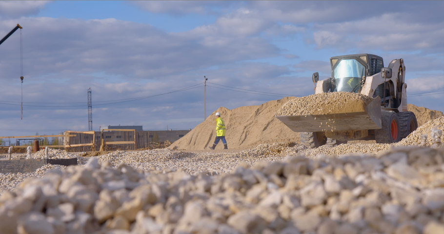 Excavation at a construction site, mini loader bobcat transports crushed stone to different construction places, where it is advisable to use compact construction equipment Royalty-Free Stock Footage #1080463388
