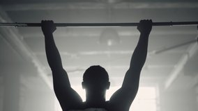 Back view muscular man doing wide grip pull ups on horizontal bar. Powerful athlete pumping arm muscles with chin ups in gym. Strong bodybuilder making intensity training during training session - Powered by Shutterstock - Get 15% off with code: PIKWIZARD15