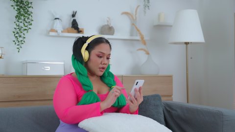 A cute fat woman dressed a variety of beautiful colors, wearing headphones, listening to music while dancing to the rhythm of the music playfully. Living without stress and activities relax concept.