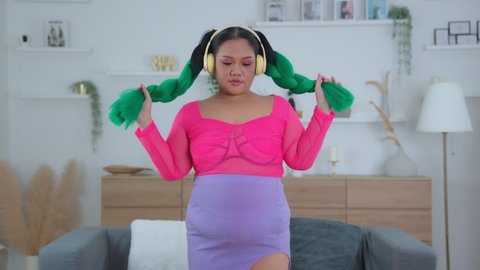 A cute fat woman dressed a variety of beautiful colors, wearing headphones, listening to music while dancing to the rhythm of the music playfully. Living without stress and activities relax concept.