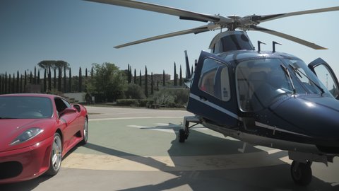 ROME,ITALY-AUGUST,22,2021: luxury life ,a private Ferrari car and helicopters awaiting their owner