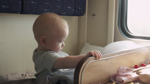 Family with little child traveling by train, cute 6 months old baby boy lying on seat by window in a compartment train. High quality 4k footage