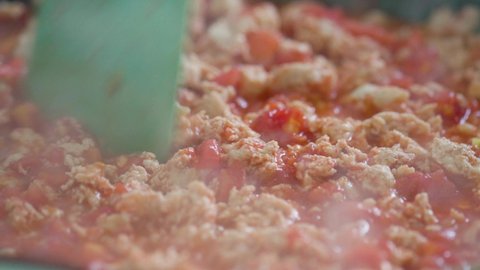 Frying and stirring mince meat. Minced meat is cooking in a frying pan. Stirring minced chicken with tomatoes with a silicone spatula. Close-up