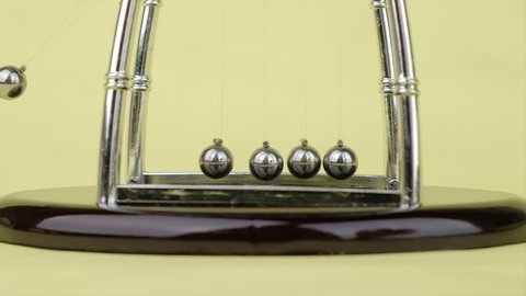 Slow motion, Newton's Cradle metal balls on green nature background, swinging metal balls, Close up.