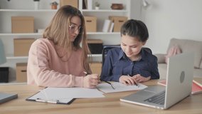 Young Woman-mentor Helping Teenage Girl Study, Do Homework, Using Laptop at a Table in the Living Room at Home. School Homeschooling. Individual Sessions. Tutoring. Early Development.
